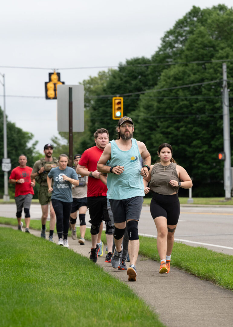 Group of people jogging on sidewalk.