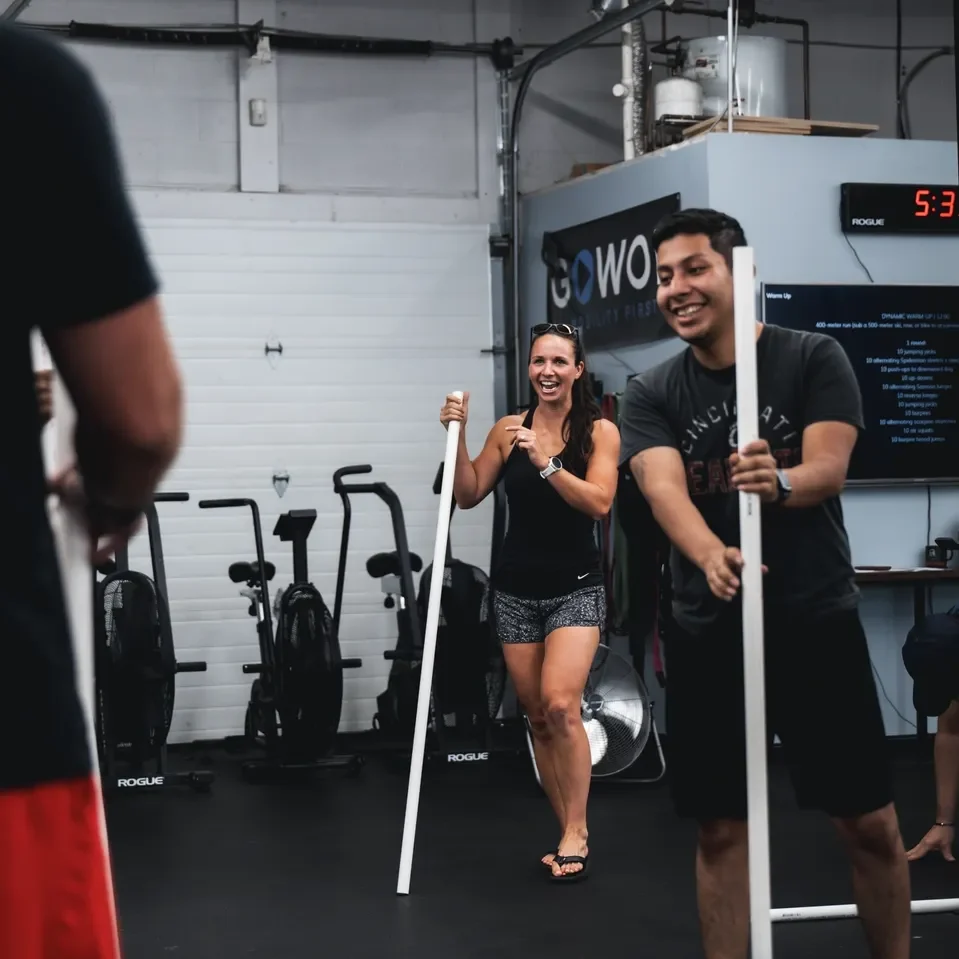 People holding poles in gym workout.