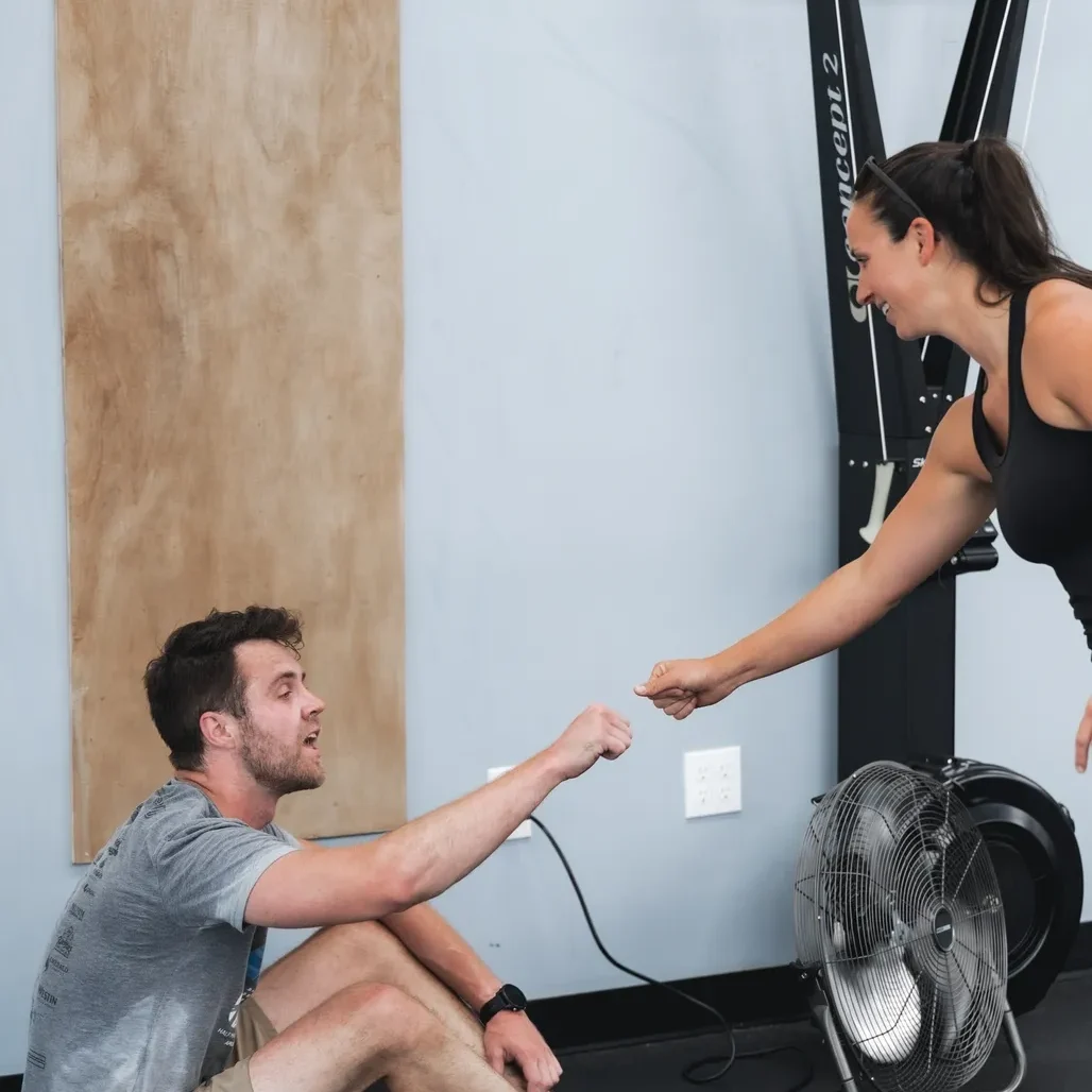 Here's an alt tag for the image: Man and woman fist-bumping in gym.