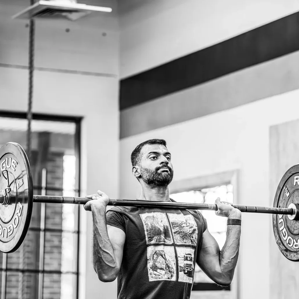 Man performing barbell back squat.